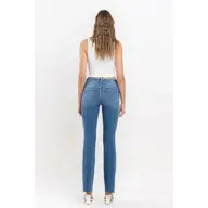 Mid rise medium wash denim boot cut jean with front and back pockets, zipper and fly closure, raw edge hem.