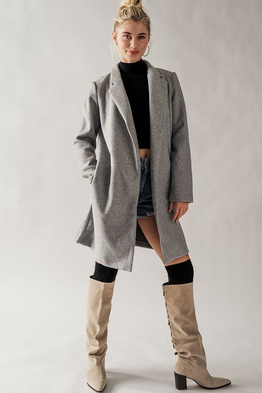 Grey overcoat with front lapels and side pockets, midi length.